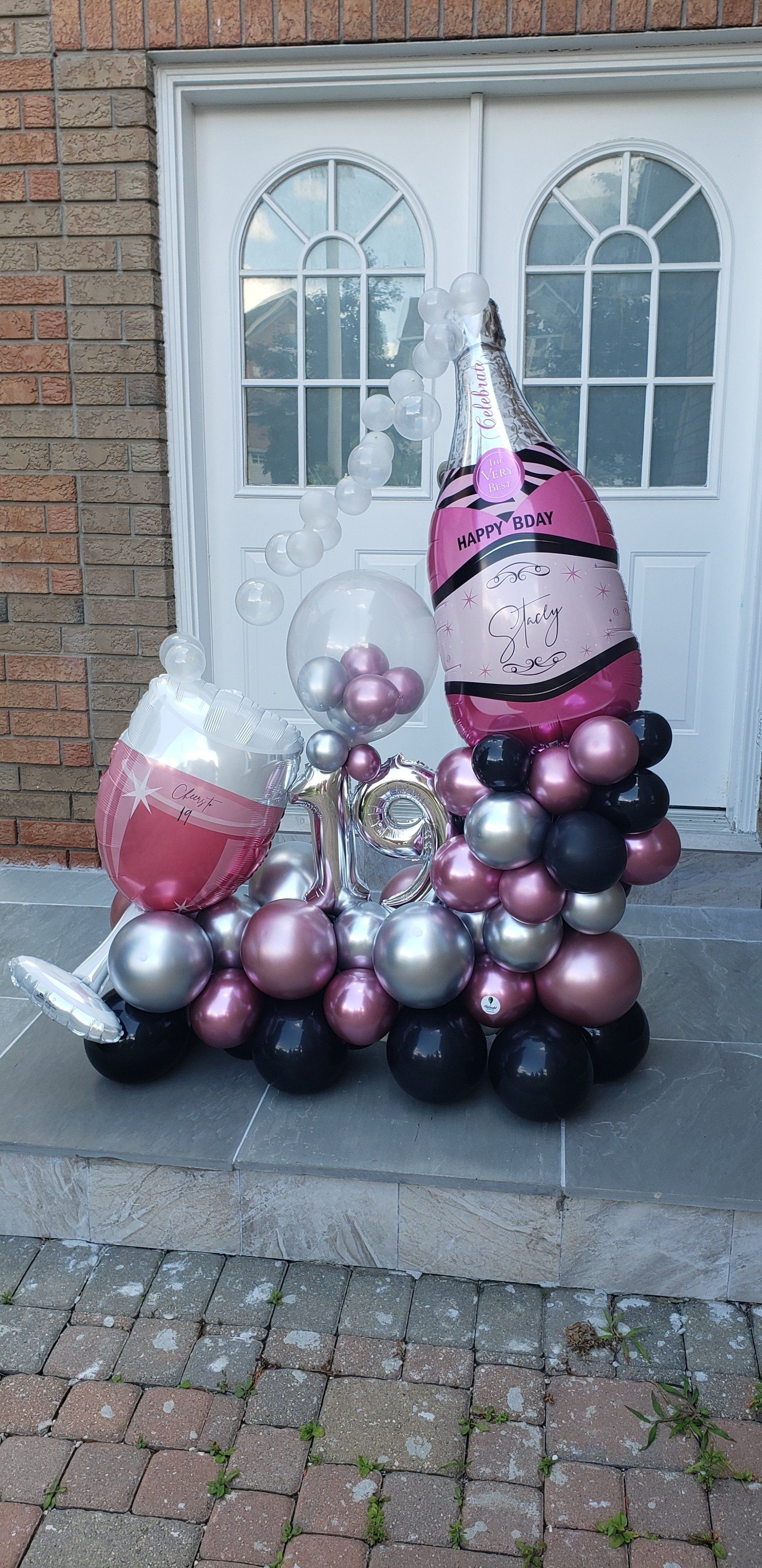 A bunch of balloons are sitting on the sidewalk in front of a building.
