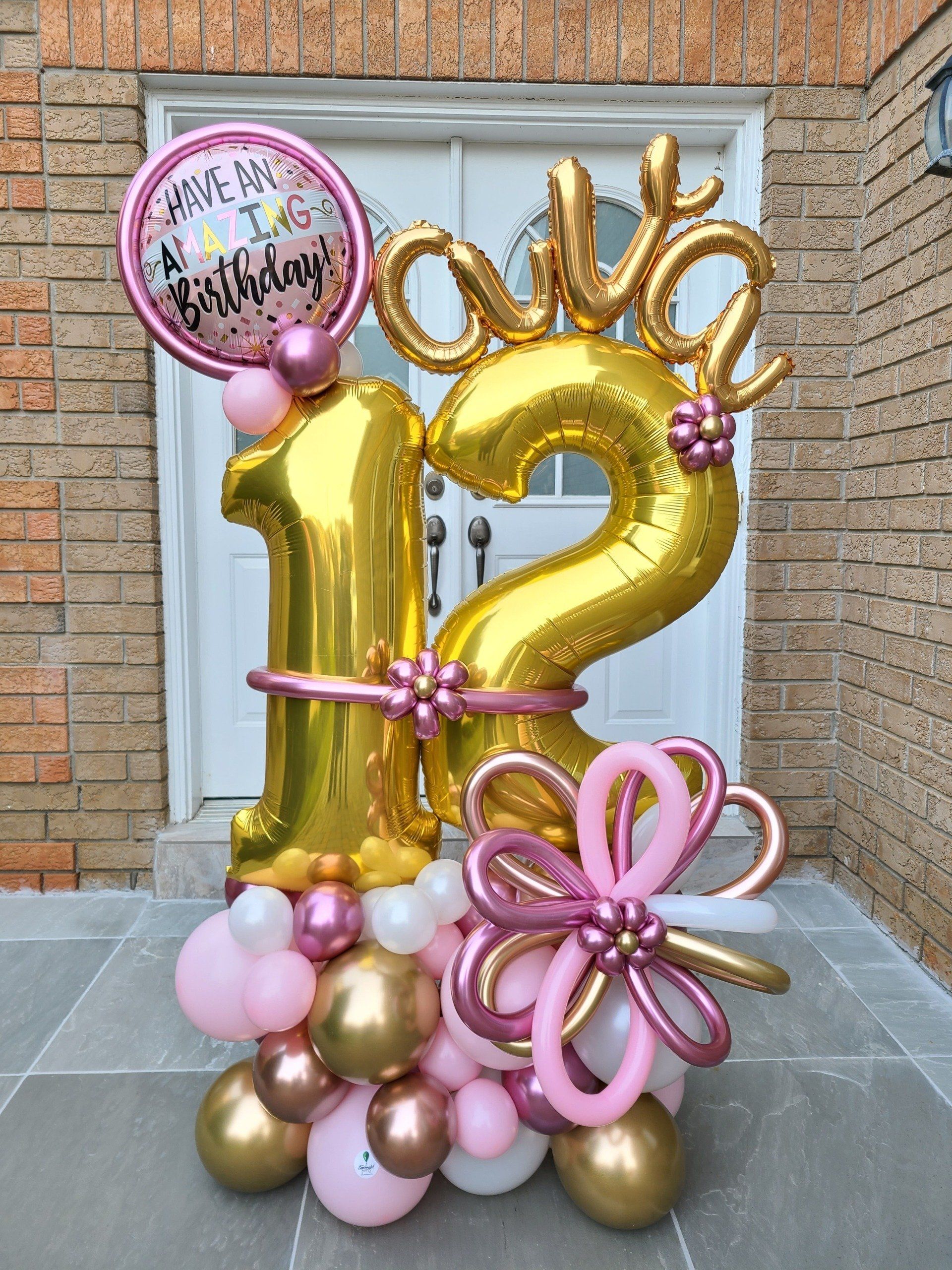 A bunch of balloons are sitting on the ground in front of a brick building.