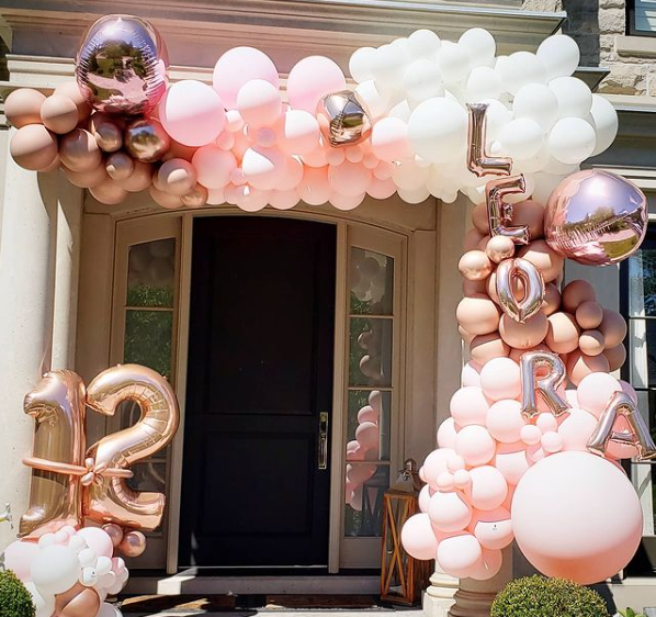 The front door of a house is decorated with pink and white balloons.