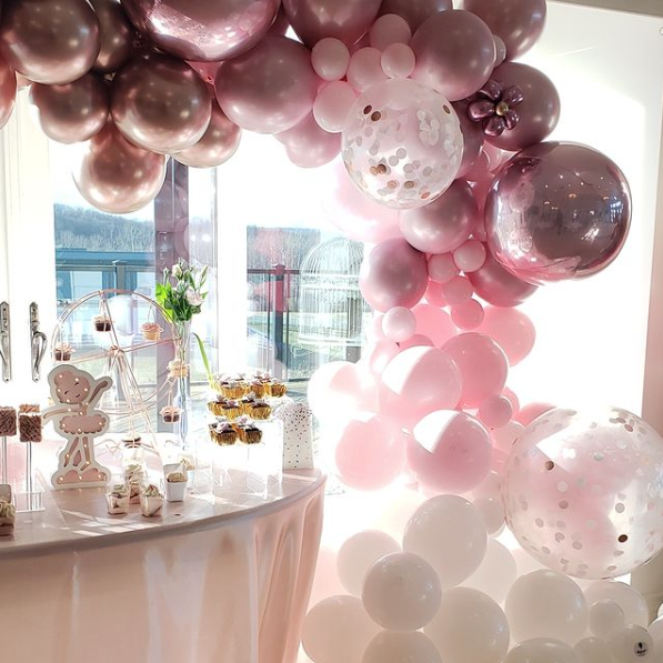 A room filled with pink and white balloons and a candy bar.