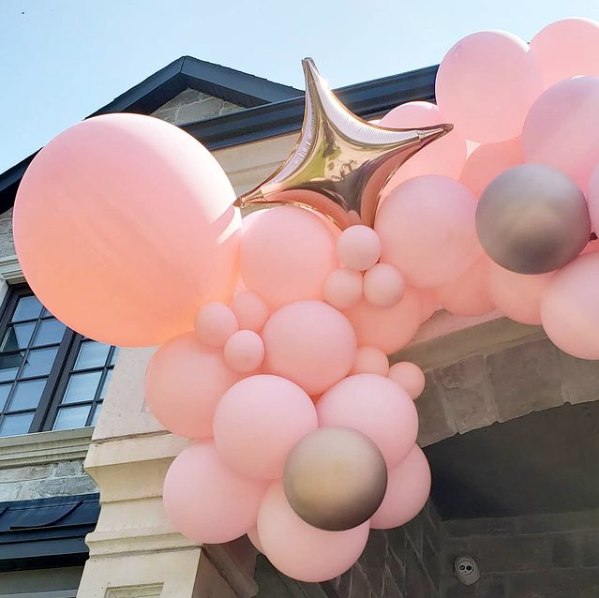 A bunch of pink balloons are hanging from a building.