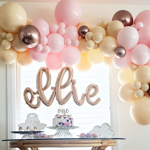 A room decorated with pink and gold balloons and a cake on a table.