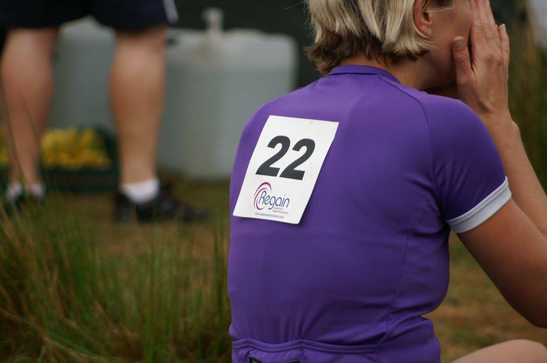 Lady sat on the floor wearing a purple lycra top with a large number 22 on her back.