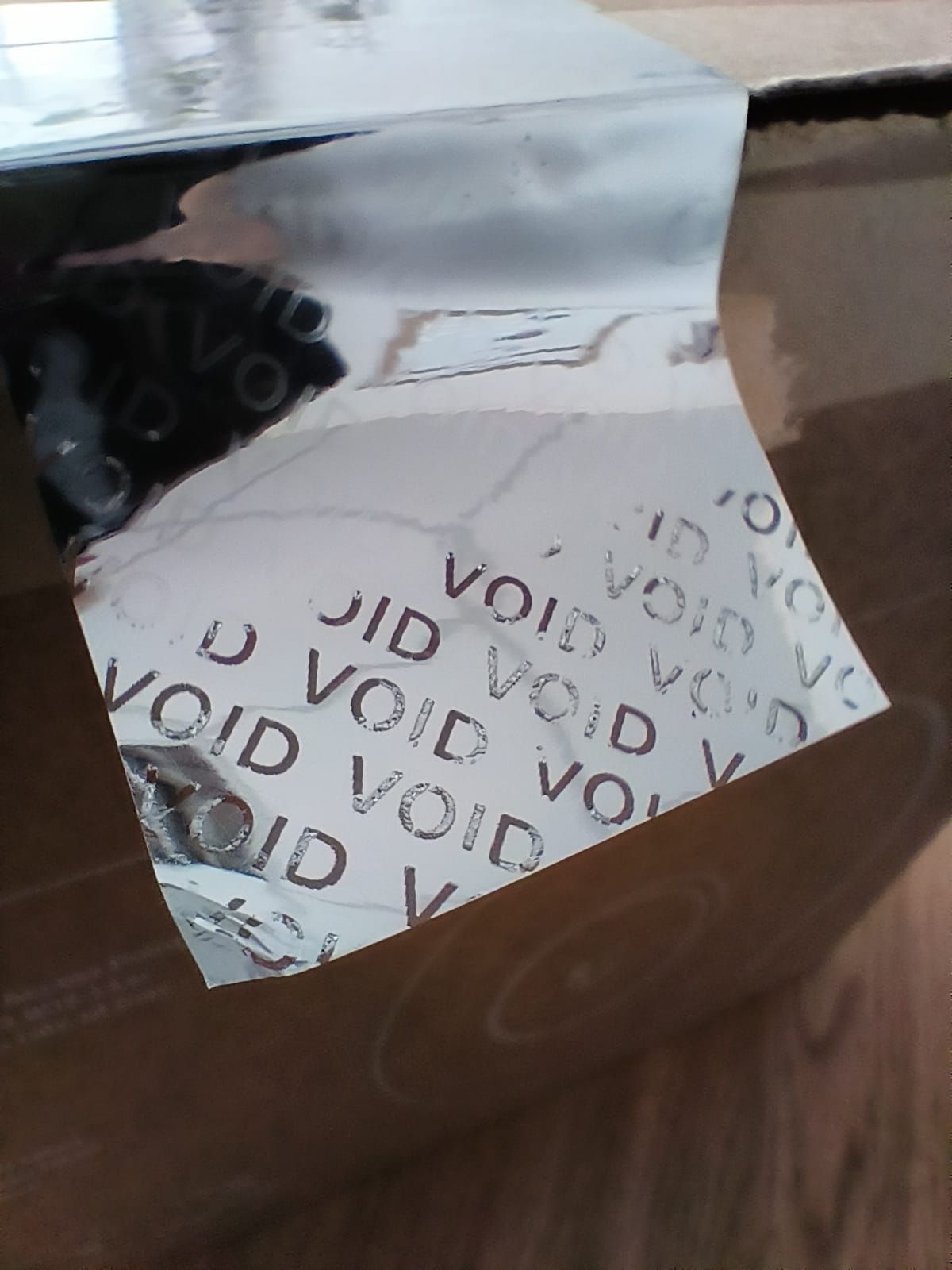 Close up of a silver 'void' tamper evident label that shows evidence of tampering