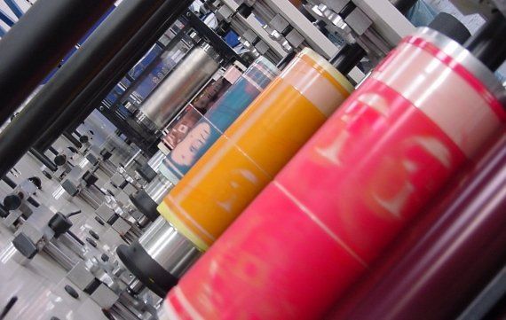 Image looking across the top of a flexographic printing press with the rollers being inked up in different colours