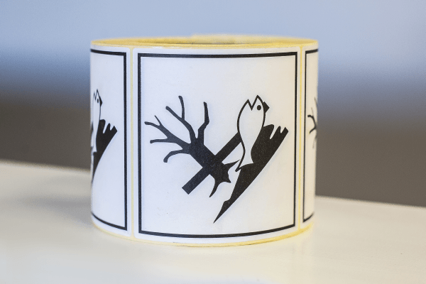 Reel of printed labels laid on its side showing the Chemical / Dangerous Goods warning pictogram