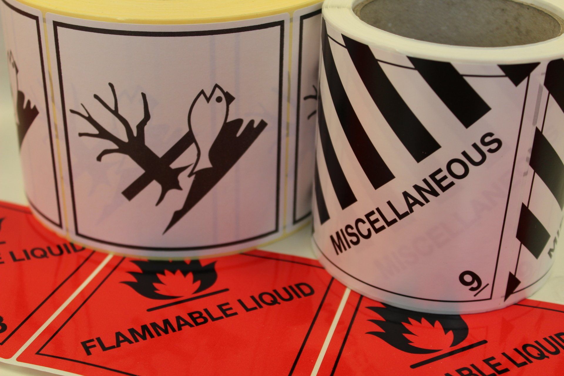 Two reels of different hazard warning pictogram labels stood on their side with another type rolled out below