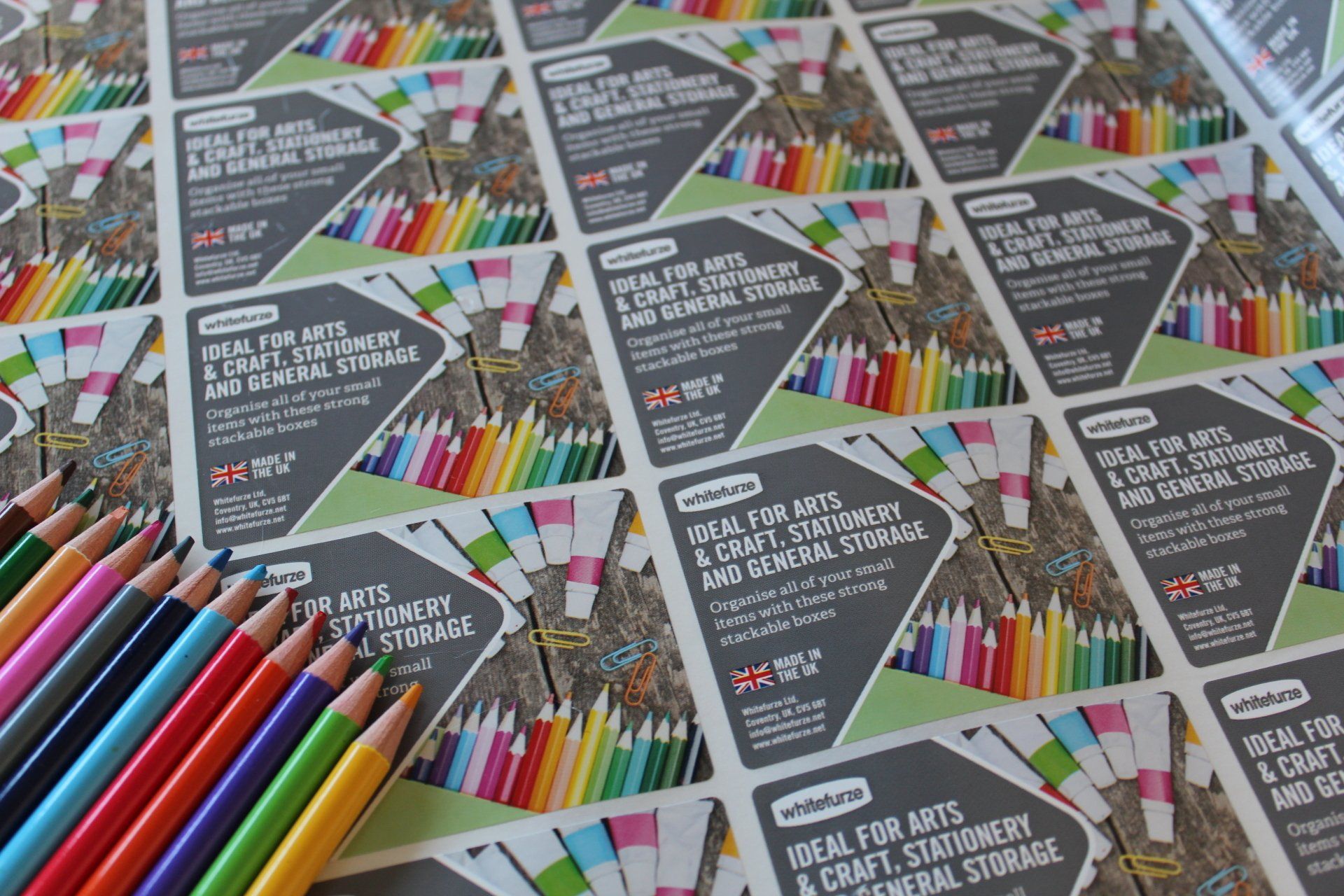A selection of colouring pencils laid on top of a reel of colouring pencil packaging labels