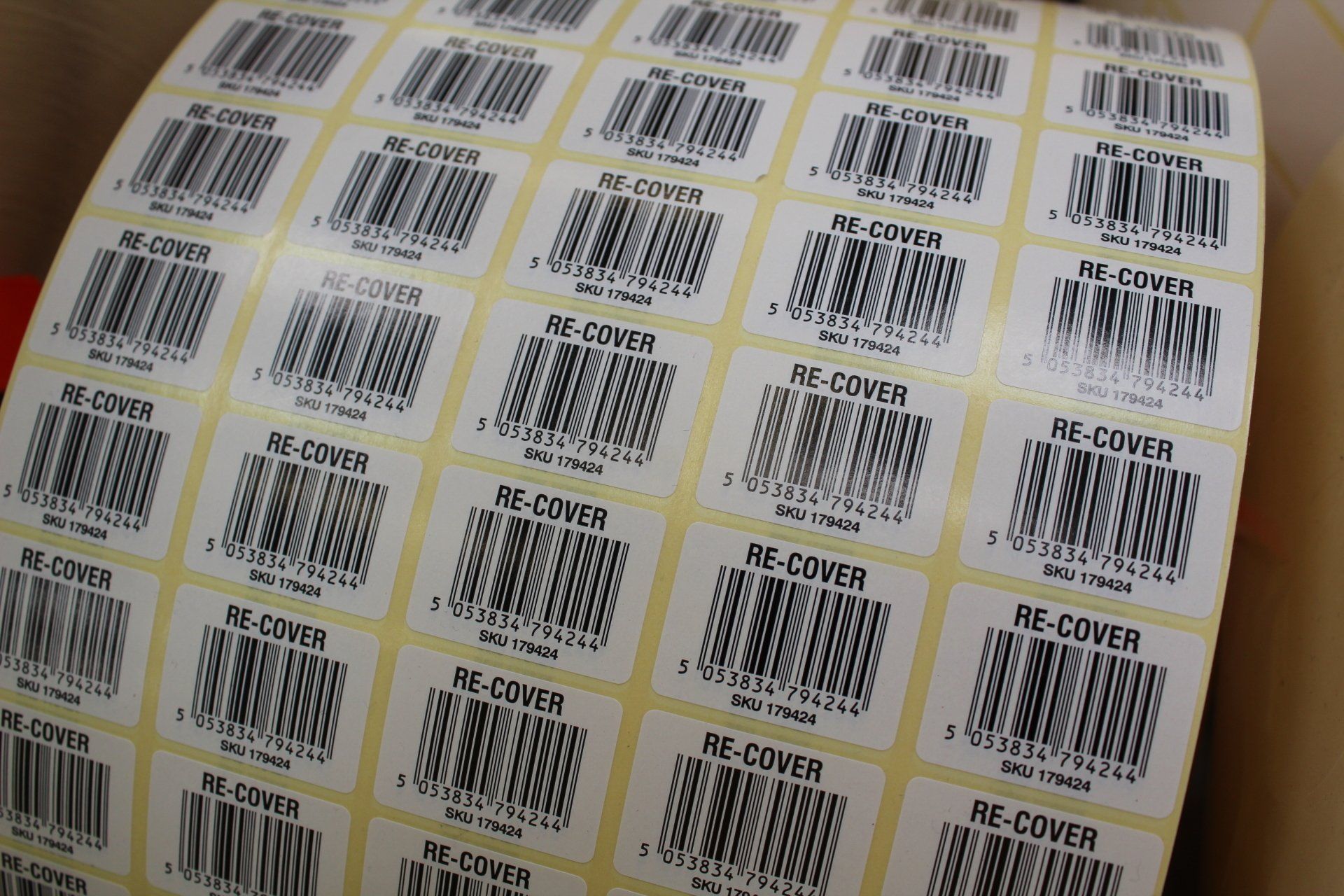 A large reel of barcode labels printed 5 across with the words 're cover' centred above each barcode