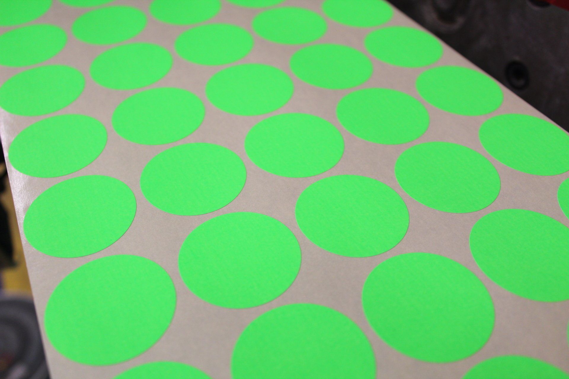 An image of a wide web of circular green dot labels printed 5 across