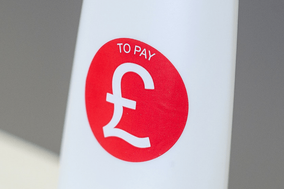 A bright red circular label stuck to a white bottle with a large pound sign in the centre of it