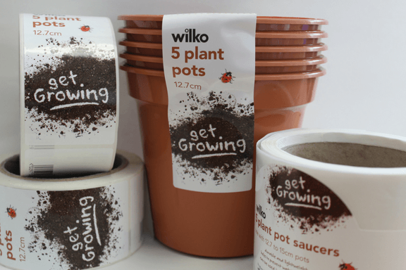 Stack of 5 plant pots with a label down the side keeping them together with 3 reels of the same finished labels by the side