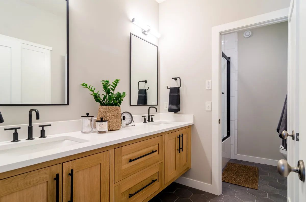 A bathroom with two sinks , a mirror , and a walk in shower.