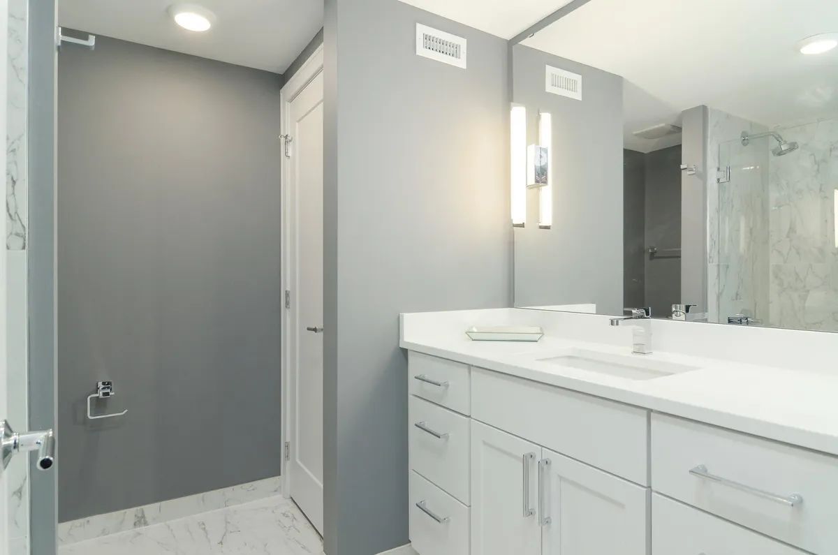 A bathroom with a sink , mirror and walk in shower.