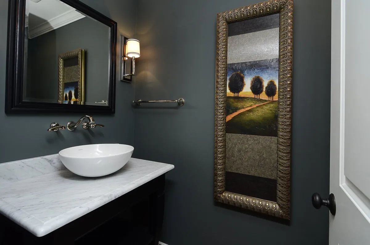 A bathroom with a sink a mirror and a picture on the wall