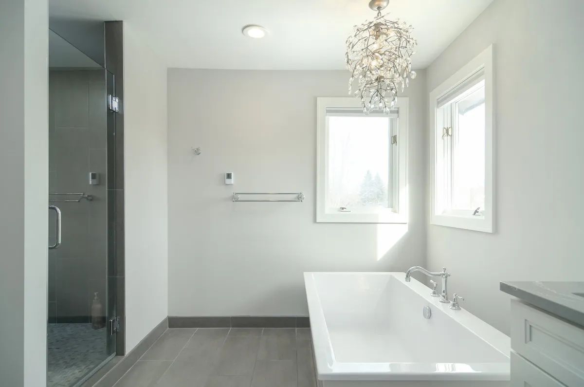 A bathroom with a bathtub , shower and window.