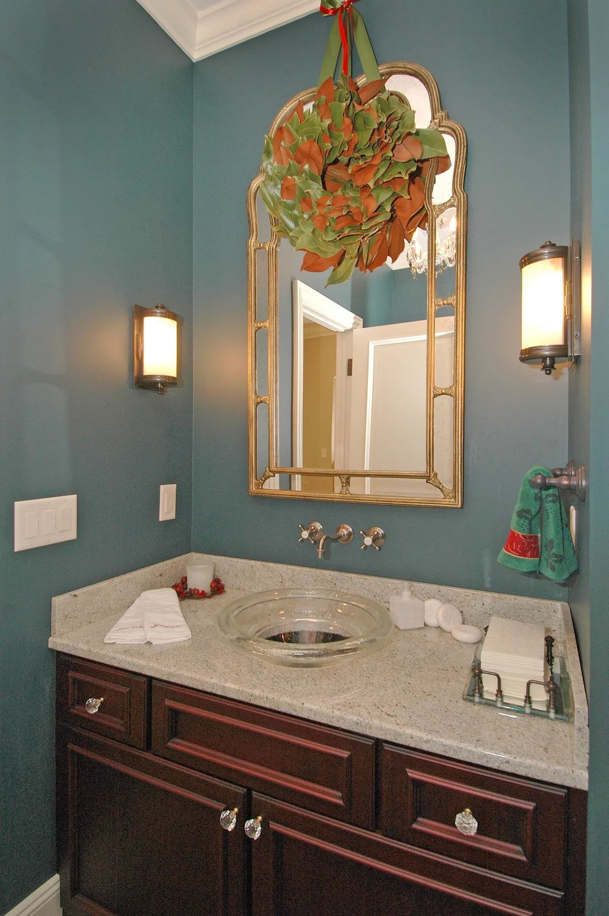 A bathroom with a sink a mirror and a wreath hanging from the ceiling