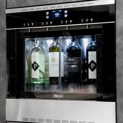 Four bottles of wine are in a stainless steel wine cooler