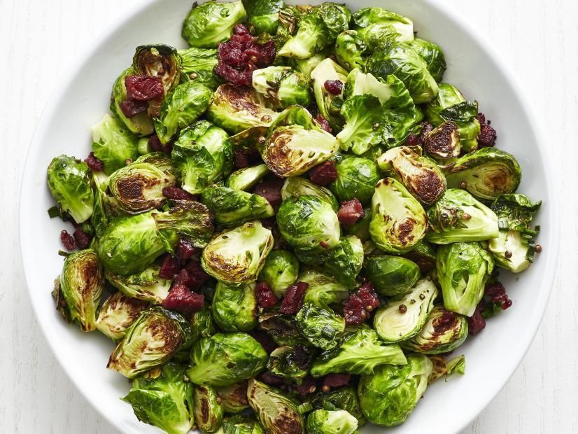 A white bowl filled with brussels sprouts and cranberries.