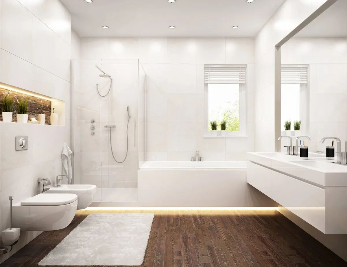 A bathroom with a bathtub , toilet , bidet , sink and mirror.