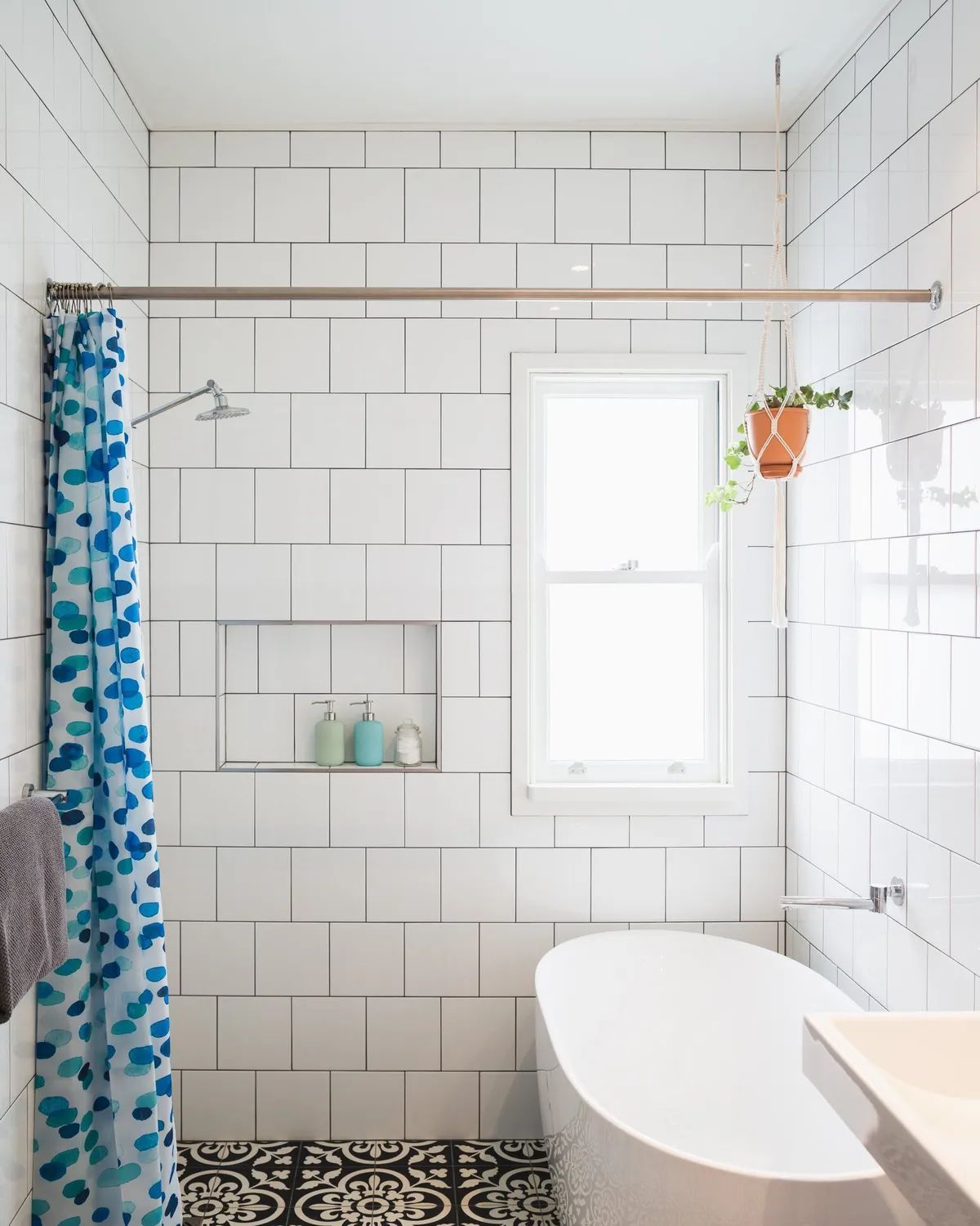 A bathroom with white tiles and a blue shower curtain