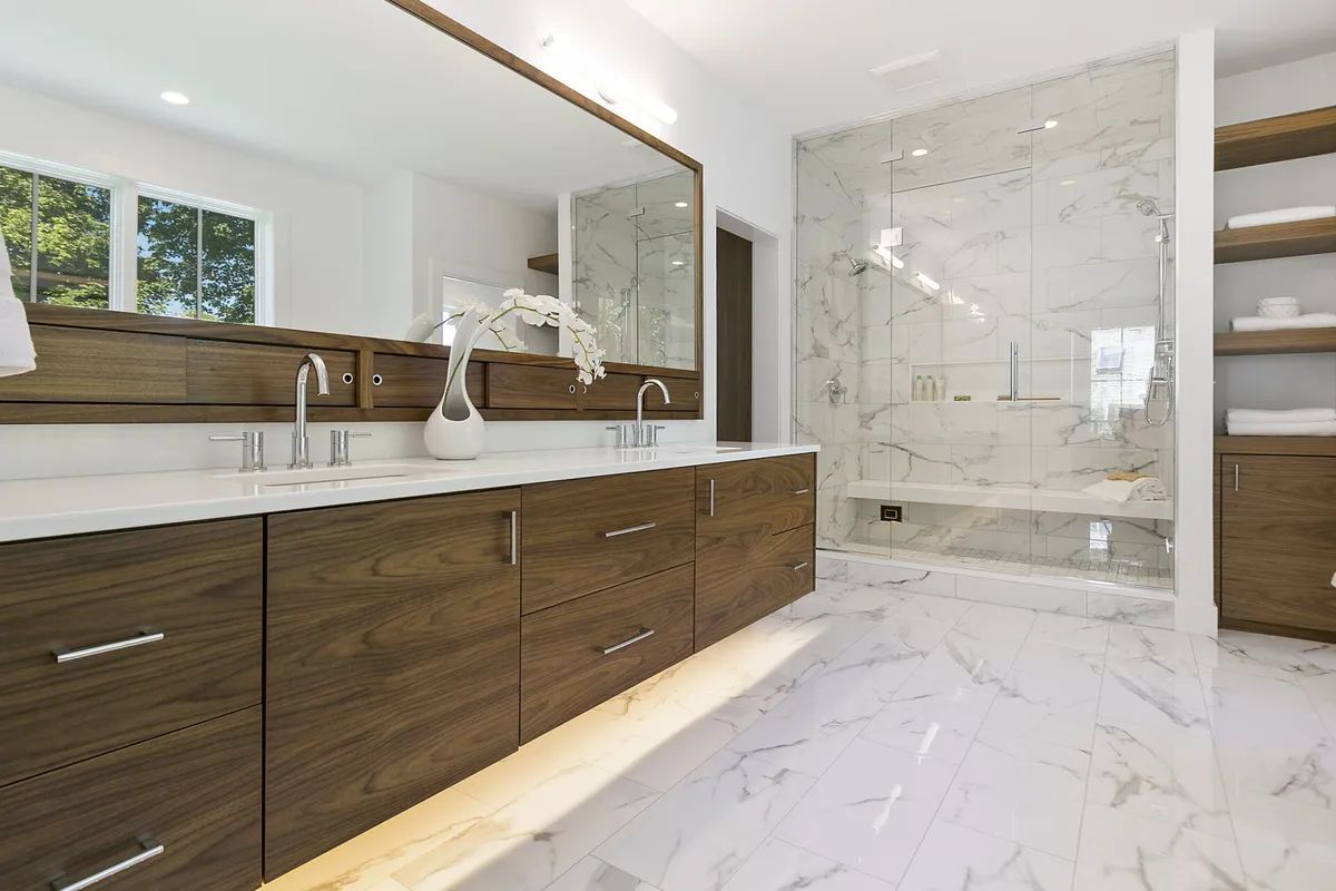 A bathroom with two sinks , a walk in shower and a large mirror.