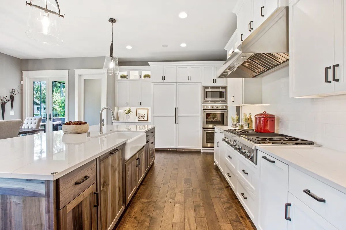 A kitchen with white cabinets , hardwood floors , and stainless steel appliances.