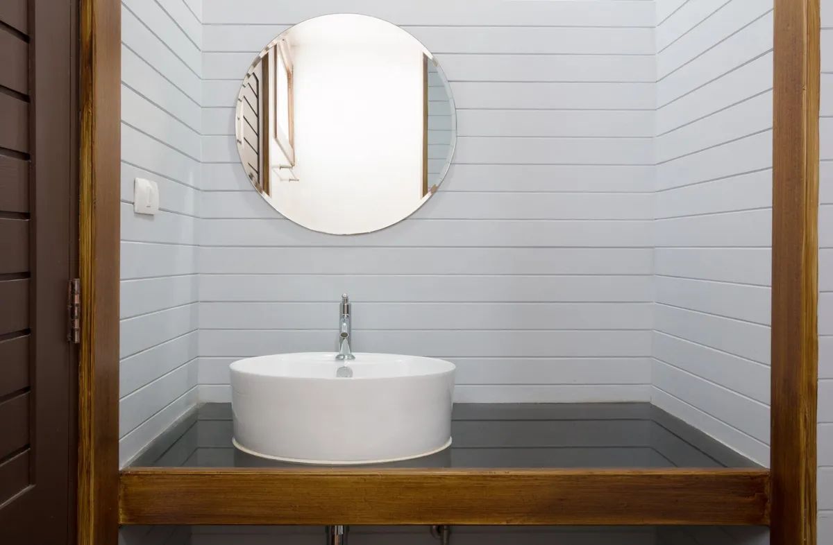 A bathroom with a sink , mirror and wooden counter top.