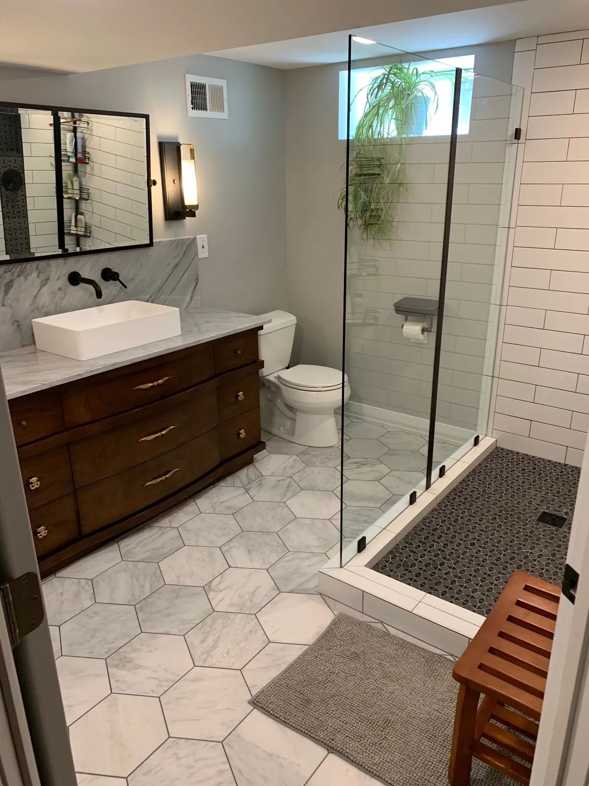 A bathroom with a walk in shower , sink , toilet and mirror.