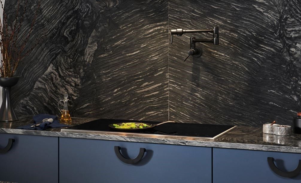 A kitchen with blue cabinets and a black wall.