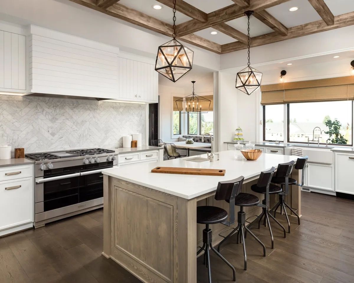 A kitchen with white cabinets , stainless steel appliances , and a large island.