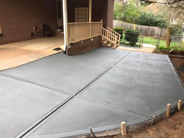 A concrete driveway is being built in front of a brick house.
