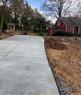 A concrete driveway is being built in front of a red house.