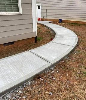 A curved concrete walkway is being built in front of a house.
