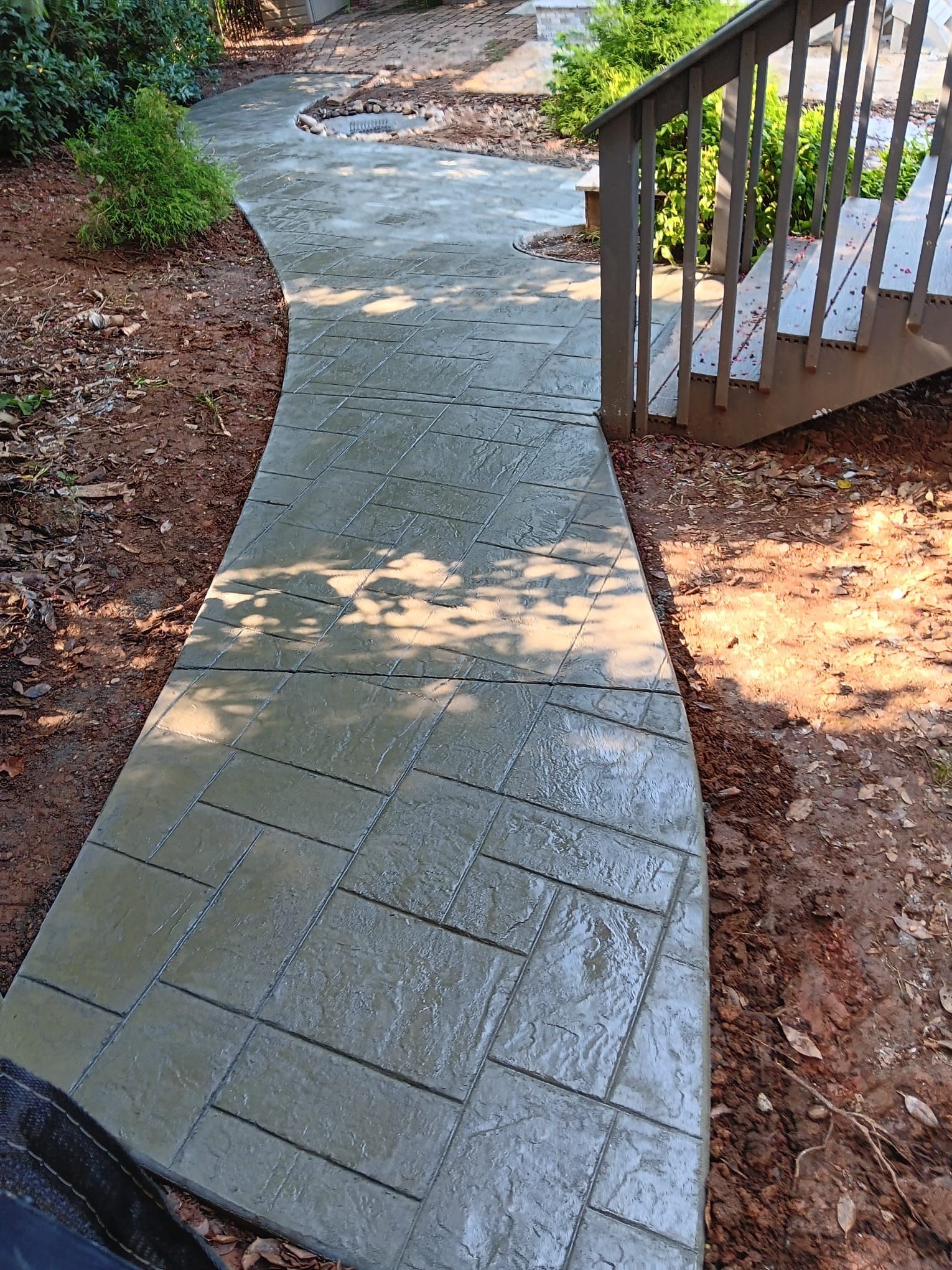 A concrete walkway leading to a deck with stairs.