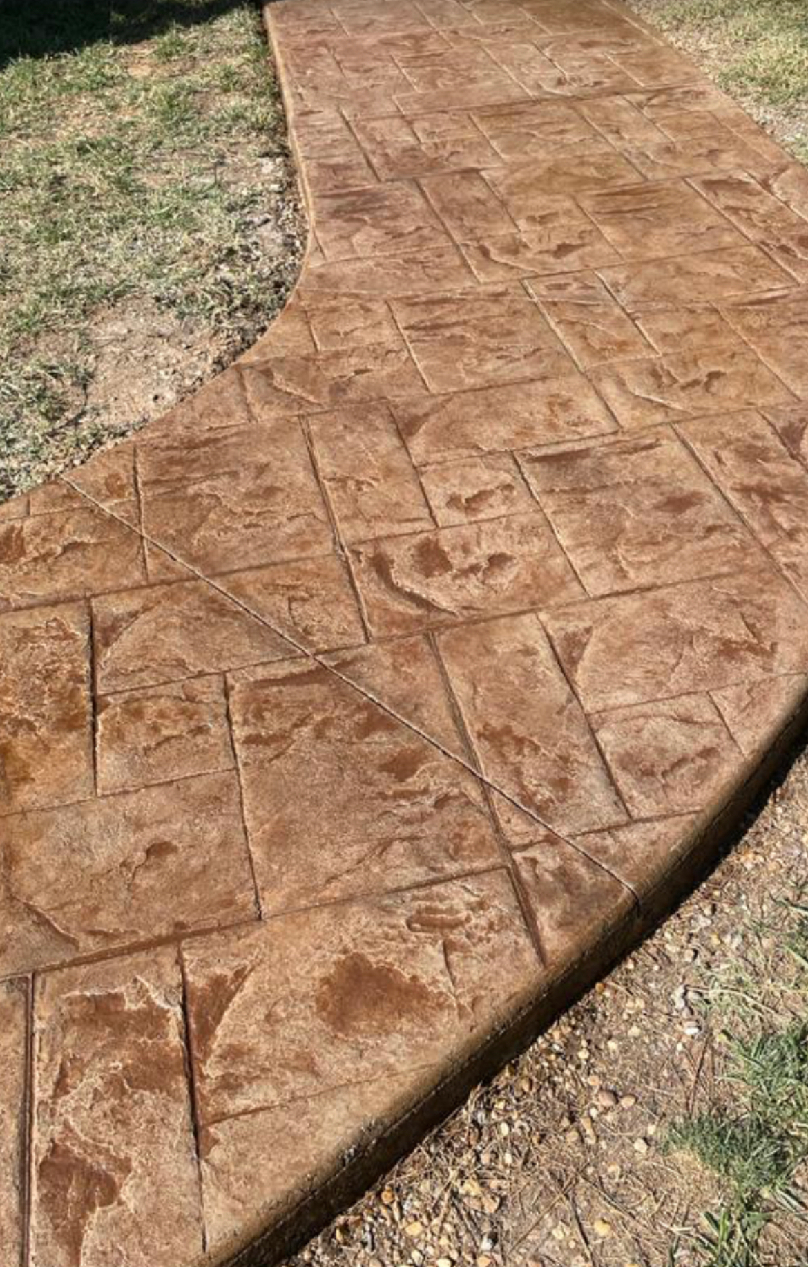 A close up of a concrete walkway in a backyard.