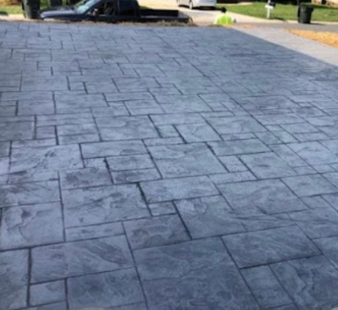 A brick driveway with a truck parked in the background