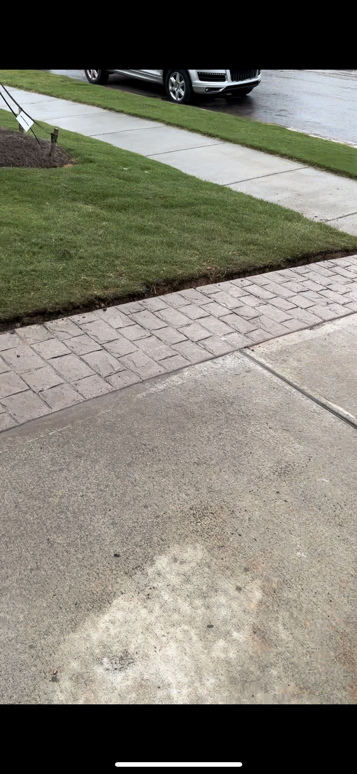 A car is parked on the side of the road next to a sidewalk.
