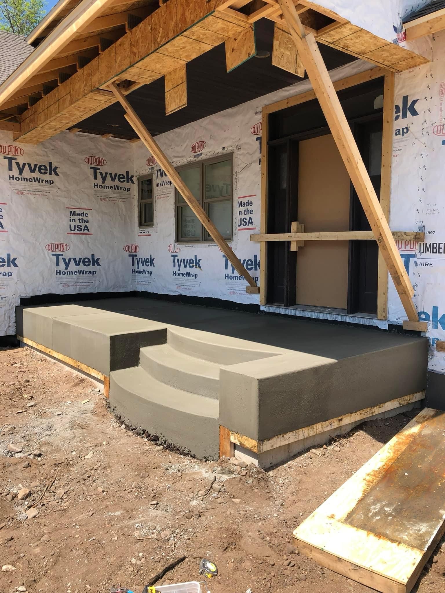 A concrete porch is being built on the side of a house.