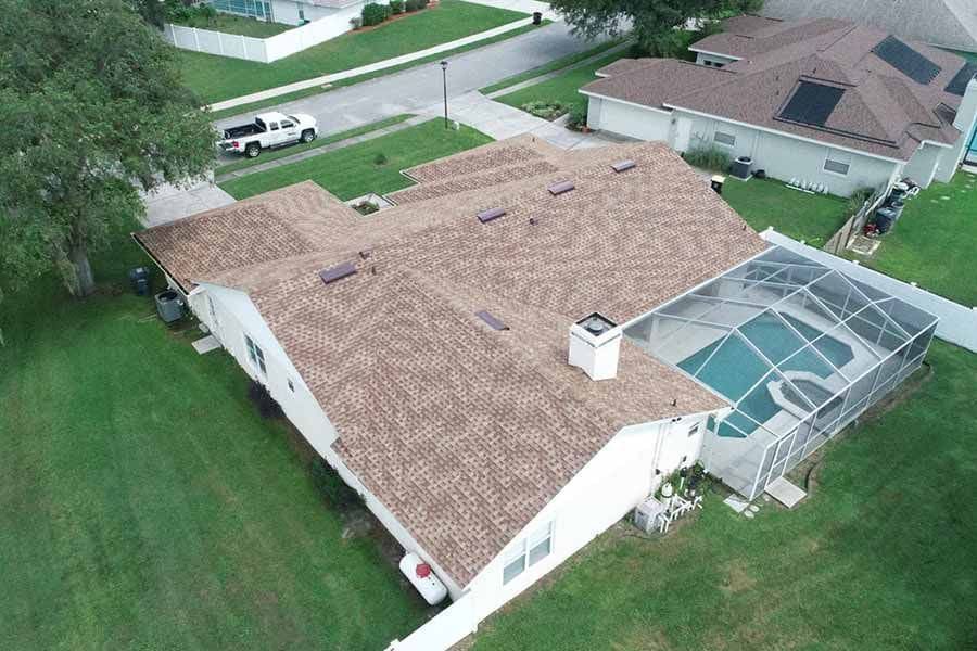 An aerial view of a house with a brown roof and a pool.