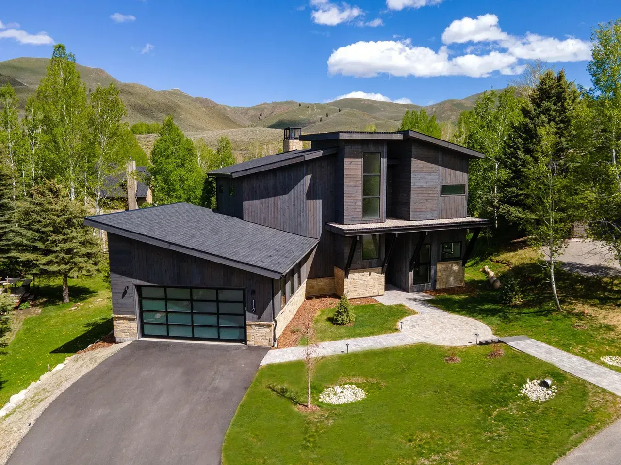 Modern living room with fireplace, sliding glass doors, light wood floors, and gray sofa.