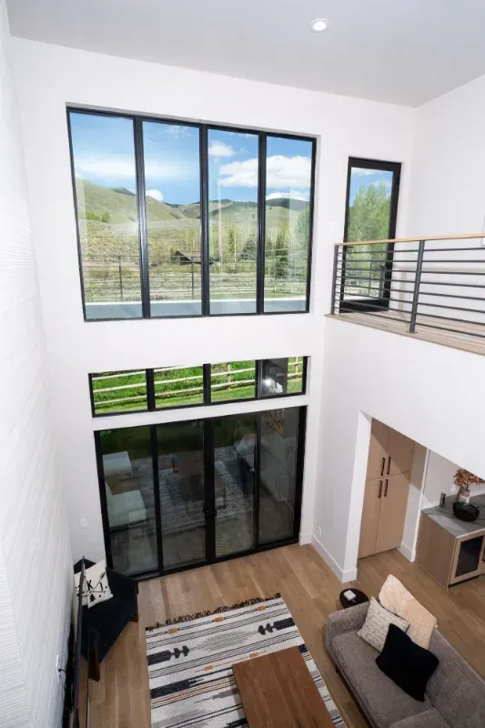 Interior with large windows, natural light. Living space with open balcony, mountain view, modern design.