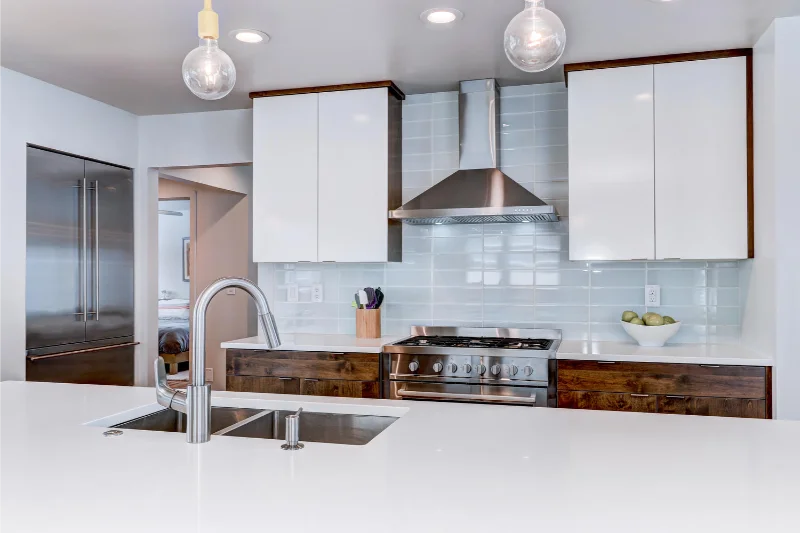 Modern kitchen with white cabinets, stainless steel appliances, and wood accents.
