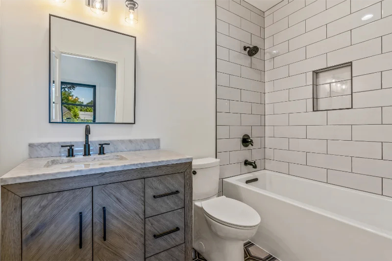 Bathroom with white subway tile shower, wood vanity, and a toilet.