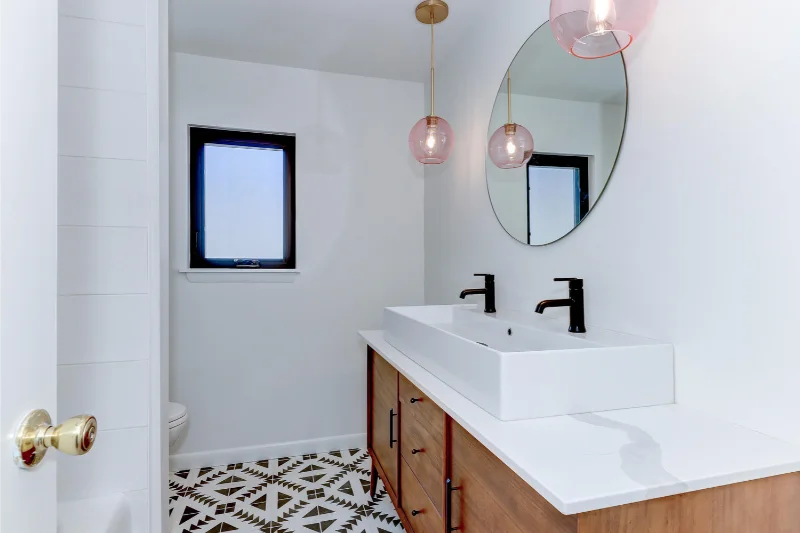 Modern bathroom with wood vanity, white sink, black fixtures, and patterned tile floor.