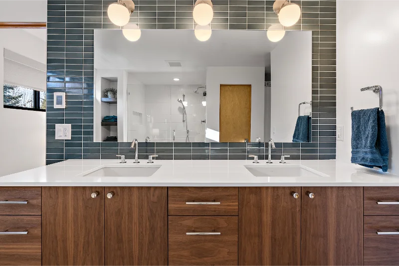 Modern bathroom with dual sinks, large mirror, and dark wood cabinets.