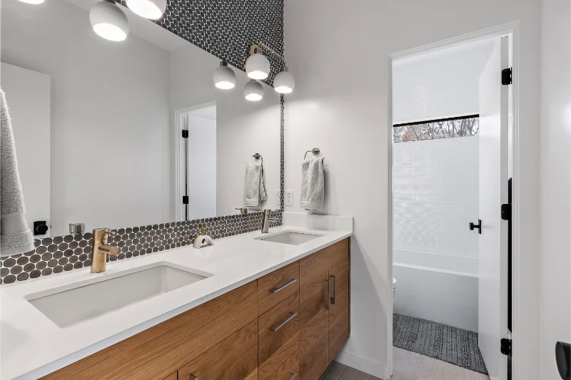 Modern bathroom with wood vanity, double sinks, and white countertops.