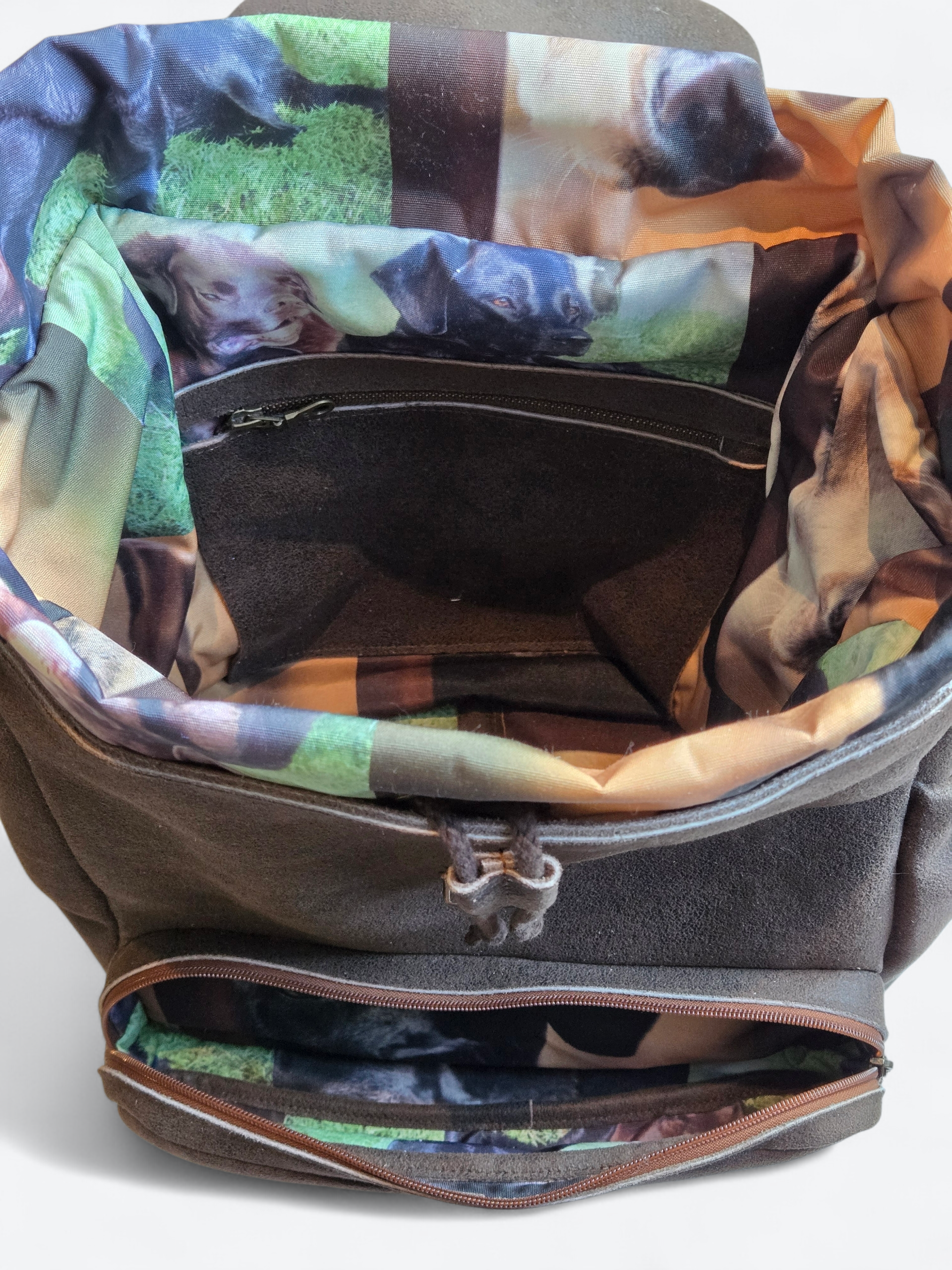 Open grijze rugzak met bloemenprint aan de binnenkant en ritsvakken.