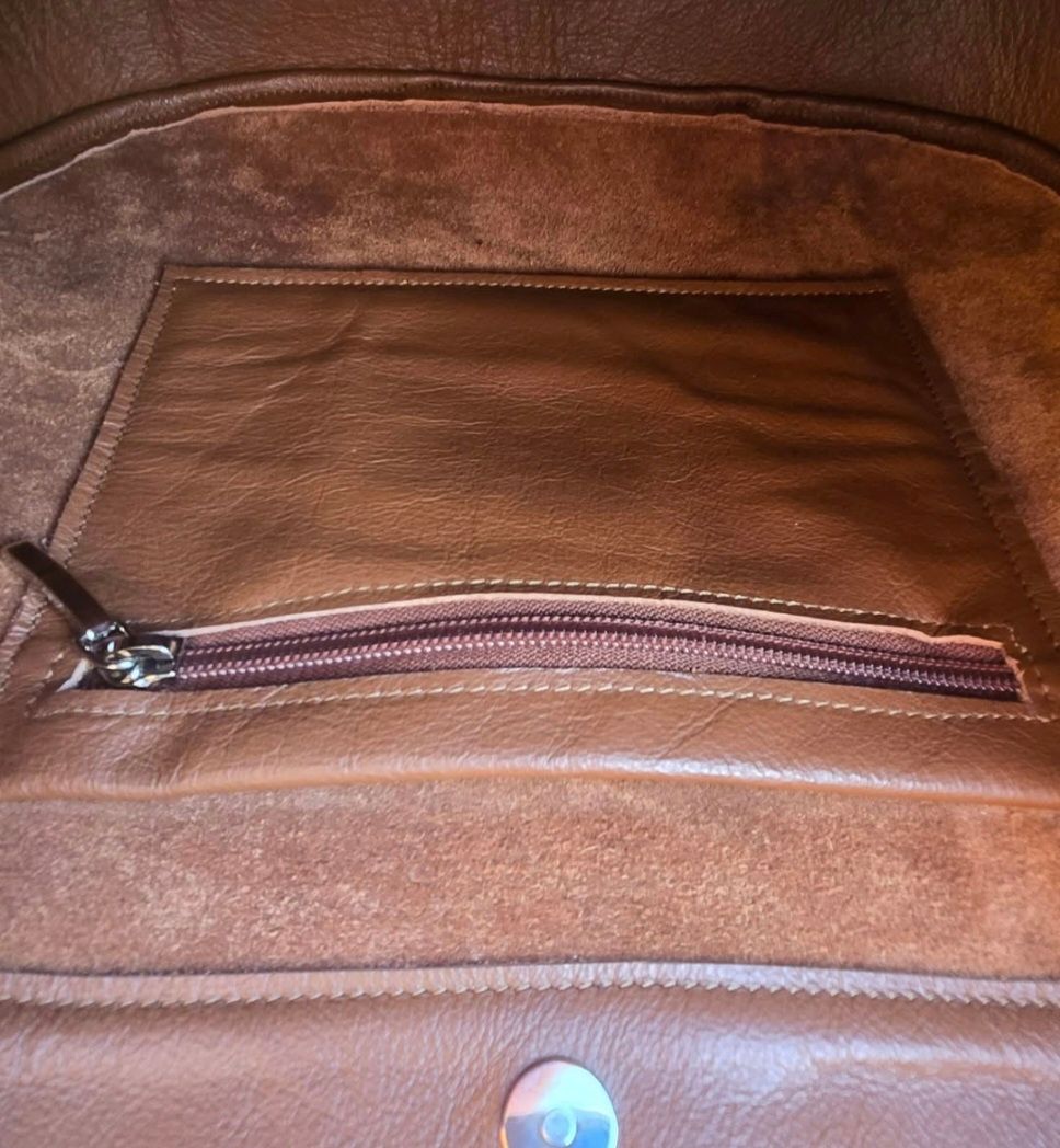 Binnenin een bruine leren tas met een ritsvak.