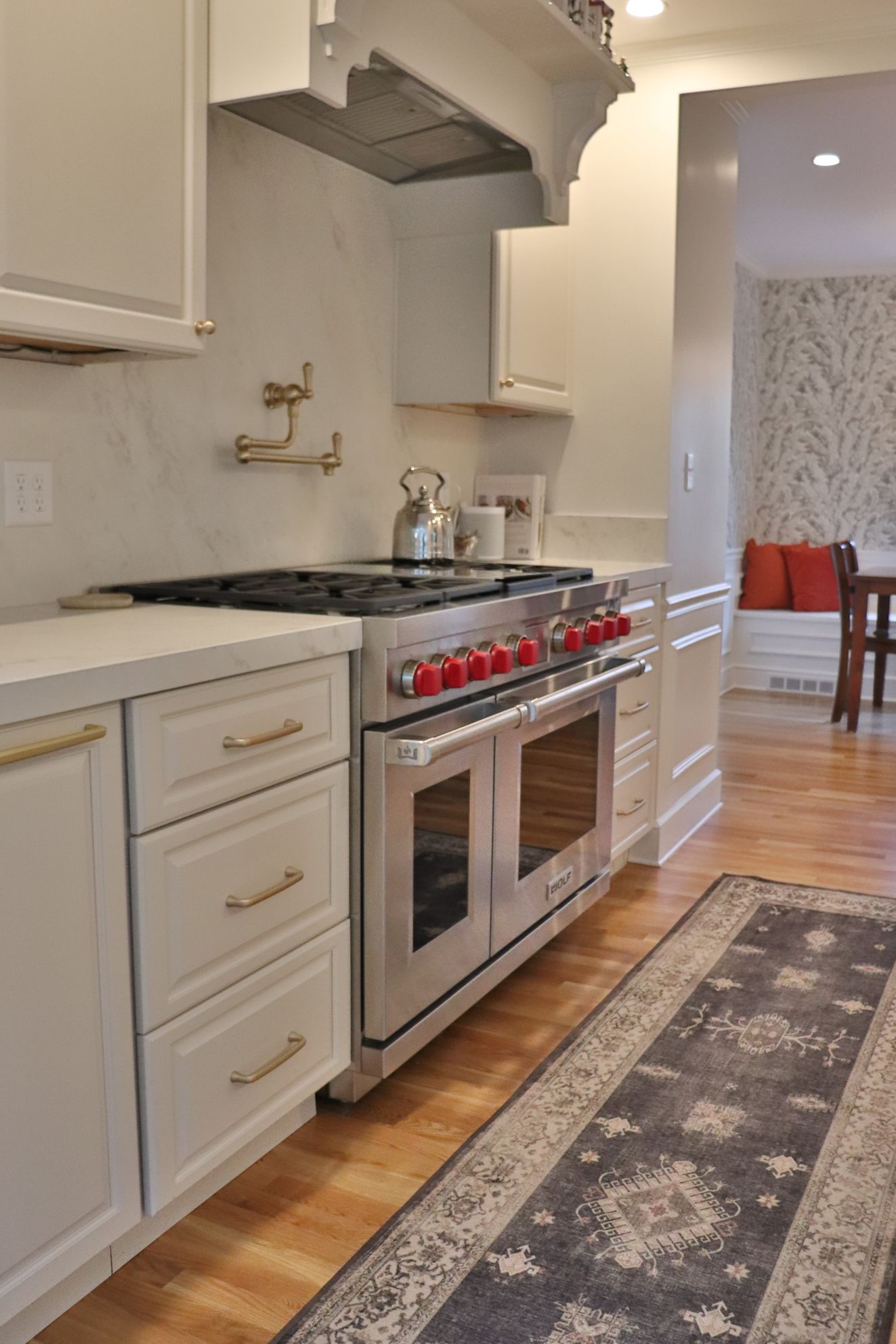 A kitchen with a stove and a rug on the floor
